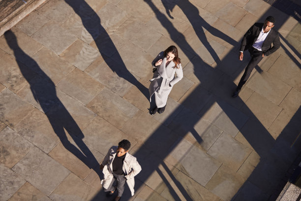 鸟瞰图，三个商人走在同一方向的阳光城市街道，水平图片下载