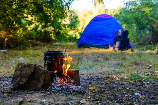 用水壶在篝火上煮食物。帐篷的背景图片下载