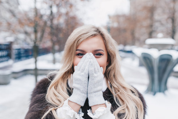 户外写真的年轻美丽时尚微笑的女孩穿着时尚的毛皮冬衣，，在白雪覆盖的街道摆姿势。图片下载