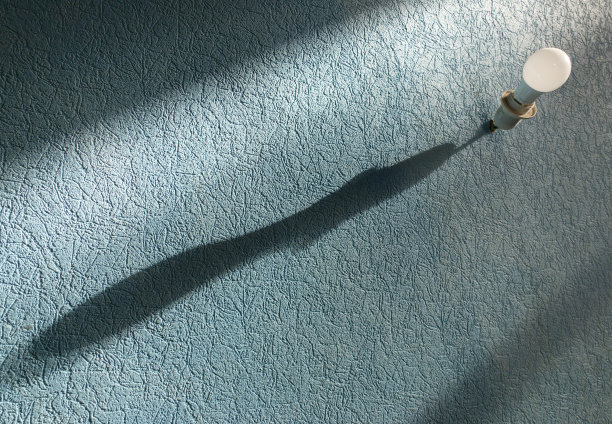 在蓝色的墙上有一个清晰的影子的电灯泡图片下载