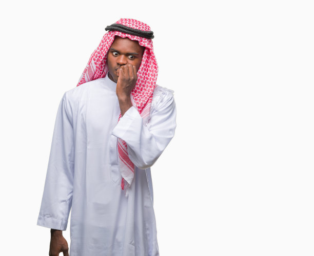 年轻的阿拉伯裔非洲人穿着传统的keffiyeh在孤立的背景下看起来紧张和紧张，手在嘴上咬指甲。焦虑的问题。图片下载