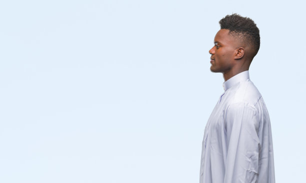 年轻的阿拉伯裔非洲男子穿着传统djellaba在孤立的背景看向一边，放松的侧面姿势，自然的脸与自信的微笑。图片下载