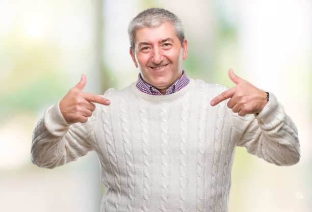 英俊的资深男子穿着冬季毛衣在孤立的背景下看着自信，脸上带着微笑，用手指指着自己骄傲和快乐。图片下载