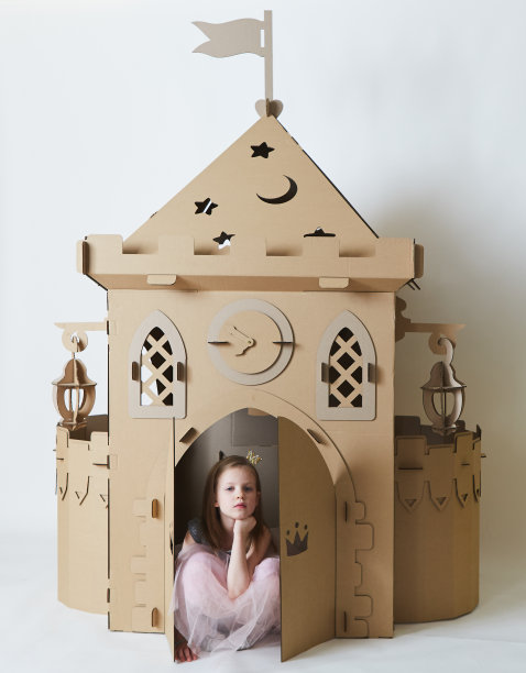 悲伤美丽的小女孩穿着公主裙玩她的玩具城堡。图片下载