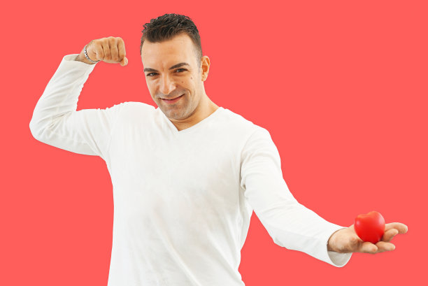 英俊的男人在红色的背景上展示红色的心。图片下载