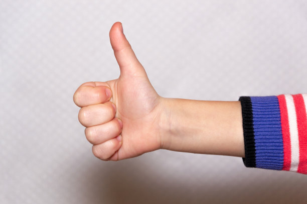 孩子的手翘起拇指，像是积极的信号。在白色背景上隔离图片下载