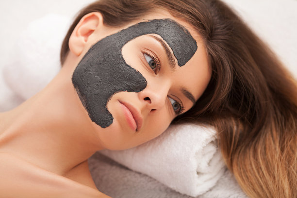 水疗中心。硬件美容。可爱的年轻女人的特写照片与奶油面膜在美容院。图片下载