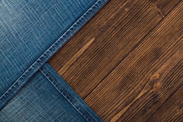 磨损牛仔裤或蓝色牛仔裤牛仔收集在粗糙的深色木制桌子背景，顶部视图与拷贝空间，旧的时尚概念。图片下载