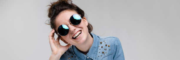 年轻的黑发女孩戴着圆眼镜。头发梳成发髻。那女孩把手放在头上。图片下载