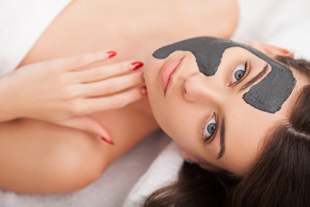 硬件美容。可爱的年轻女人的特写照片与奶油面膜在美容院。图片下载