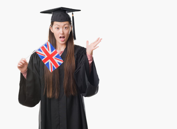 年轻的中国妇女穿着毕业制服举着英国国旗非常高兴和兴奋，胜利者的表情庆祝胜利尖叫着大大的微笑和举起手图片下载