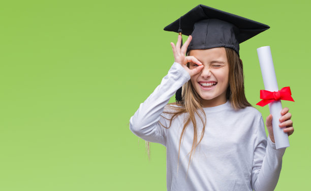 年轻美丽的女孩戴着研究生帽持有学位在孤立的背景与快乐的脸微笑做ok手势与手在眼睛看通过手指图片下载
