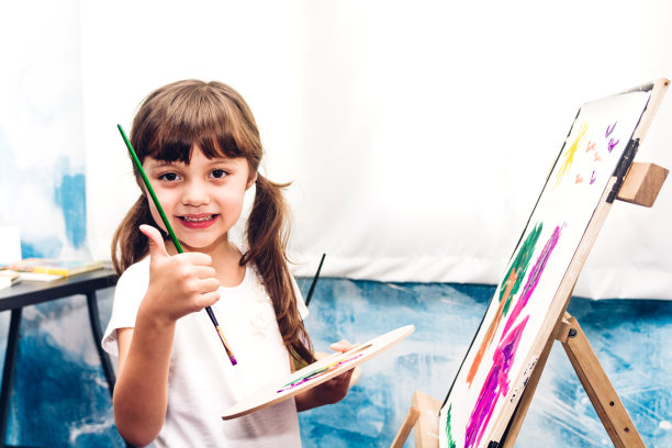 小女孩艺术家在画布上用调色板和水彩画在家里图片下载