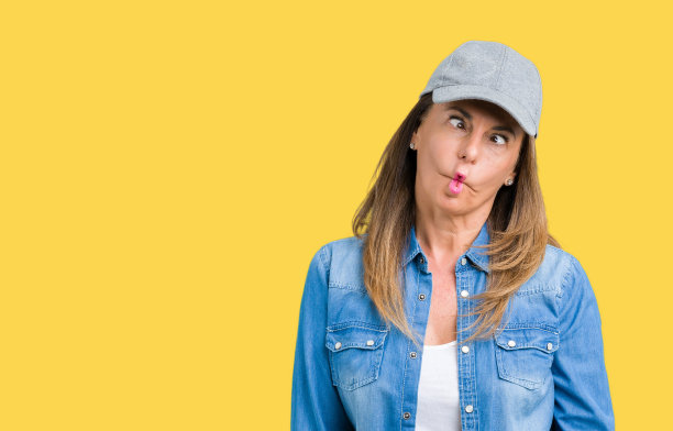 美丽的中年妇女戴运动帽在孤立的背景使鱼脸与嘴唇，疯狂和滑稽的手势。有趣的表情。图片下载