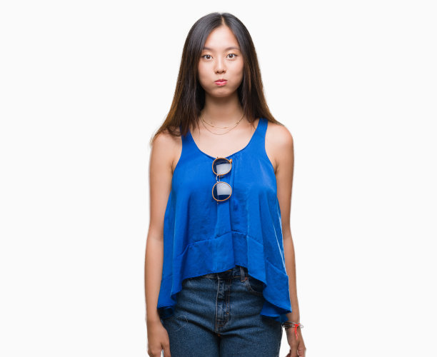 年轻的亚洲女人在孤立的背景下鼓起的脸颊与滑稽的脸。嘴巴里充满了气，疯狂的表情。图片下载