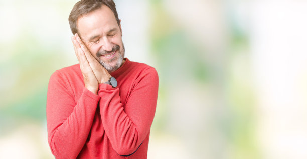 英俊的中年白发老人穿着冬季毛衣在孤立的背景睡累了，做梦，摆姿势与双手同时闭上眼睛微笑。图片下载