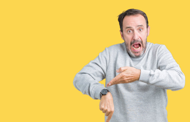 英俊的中年老人穿着一件汗衫越过孤立的背景，匆忙的指向手表时间，不耐烦，心烦和愤怒的期限延误图片下载