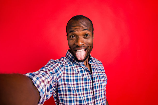 可爱的自画像英俊的有吸引力的愉快的愉快的积极的高兴的家伙穿着格子衬衫显示舌头孤立在明亮生动的亮红色背景图片下载