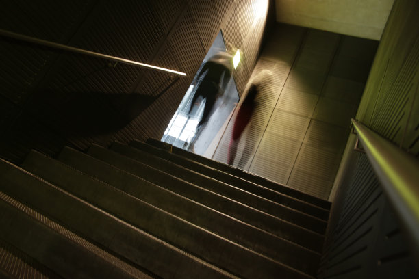 模糊的剪影，两个人正从地下上楼。关于建筑和城市生活方式的抽象照片。图片下载