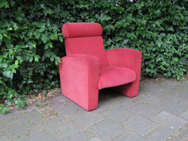 红色的大椅子站在人行道旁的一棵绿树旁图片下载