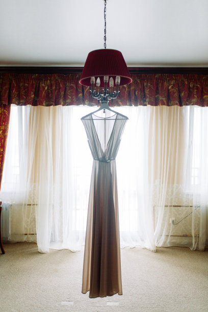 衣服，刺绣和闺房照片的细节。婚纱挂在酒店的吊灯上。图片下载
