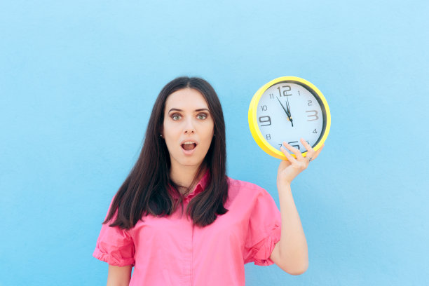 在蓝色背景下拿着时钟的快乐女人图片下载