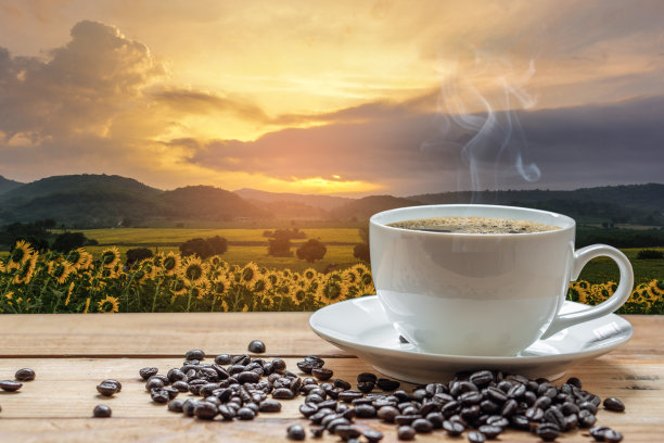 白色的咖啡杯和咖啡豆放在木桌上，与夕阳的背景自然融合图片下载