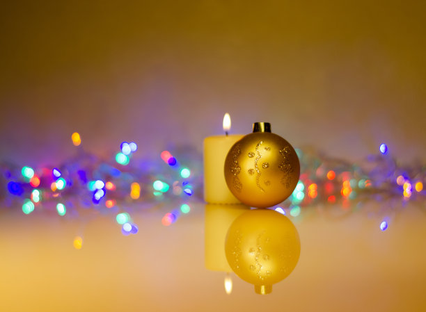 在昏暗的灯光下，金色的圣诞球和燃烧的蜡烛在花环的背景上图片下载