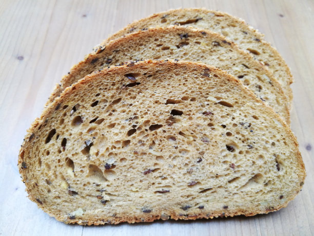 三片亚麻籽黑麦面包。平放特写照片。图片下载