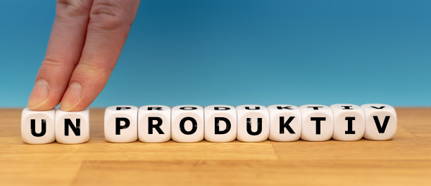 骰子形成德语单词“非生产性”(英语中的“非生产性”)，而两个手指推开字母“UN”，以改变单词“PRODUKTIV”(英语中的“生产性”)。图片下载
