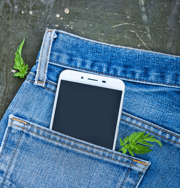 手机在牛仔裤口袋上的木制背景。俯视图图片下载