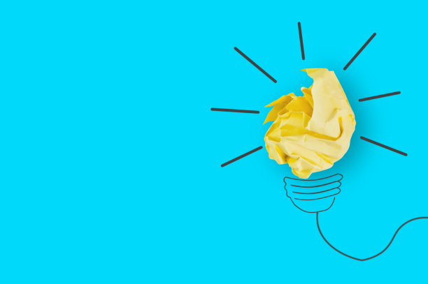 一张皱巴巴的黄纸和一张图片放在办公室的蓝色桌子上，做成了一个灯泡。前视图。灵感的概念。为你的文本复制空间图片下载