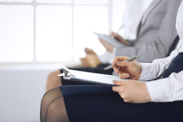 商务人士在办公室参加会议或培训，特写。女人坐在椅子上做笔记，就像排队或开会时一样。图片下载