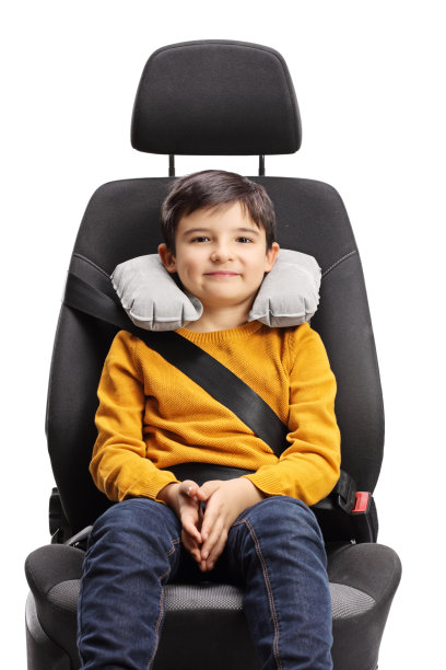 小男孩坐在汽车座椅上，枕着颈枕看着镜头图片下载