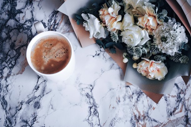 大理石桌子上放着一杯咖啡和一束花。弗拉图片下载