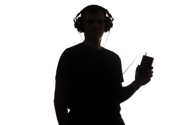 一个年轻人的剪影与智能手机和耳机图片下载