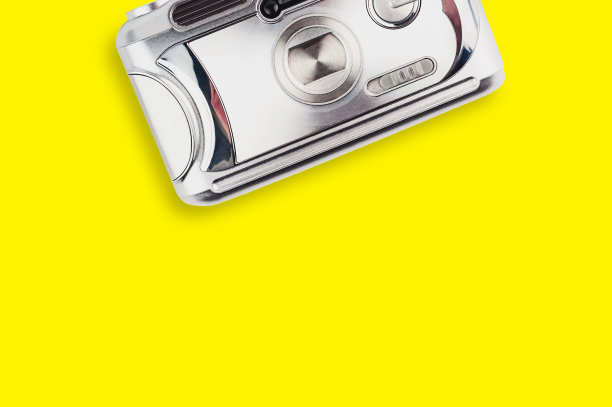 黄色桌子中央的银色塑料旧相机。前视图。旅行的概念。为你的文本复制空间图片下载