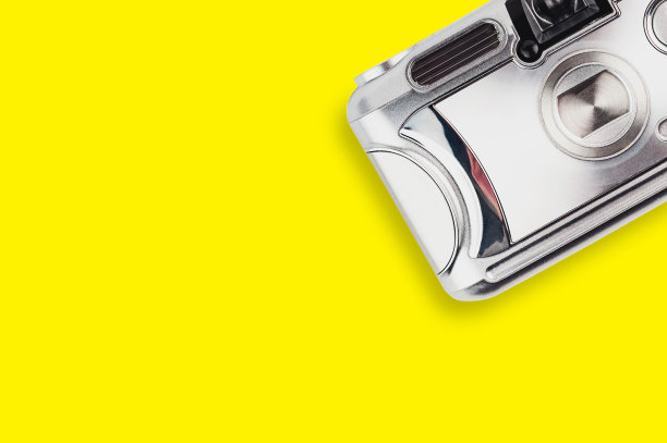 黄色桌子中央的银色塑料旧相机。前视图。旅行的概念。为你的文本复制空间图片下载