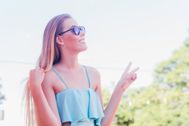 女孩穿着休闲装，戴着墨镜，做着和平手势。高级时尚都市风格照片图片下载