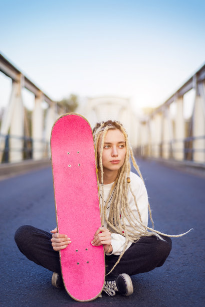 年轻女子坐在桥上，带着滑板肖像图片下载