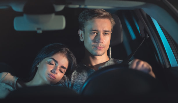 这个男人开着一辆车，车上有一个正在睡觉的女人。晚上晚上时间图片下载