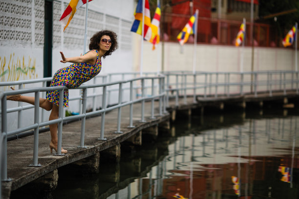 一位亚洲妇女戴着太阳镜站在河堤上。图片下载