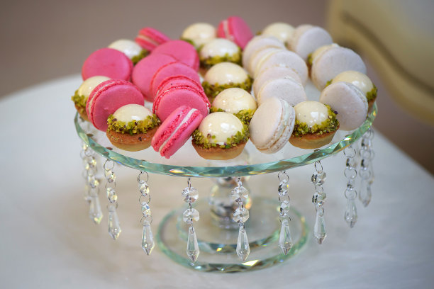 装饰的水晶蛋糕架展示了各种各样的奶油蛋糕和两种不同颜色的杏仁饼干图片下载