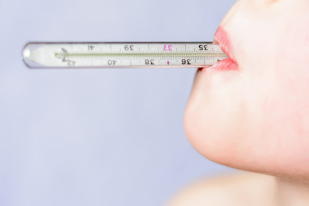 一个小男孩拿着一个温度计在一个白色的背景在他的嘴近距离图片下载