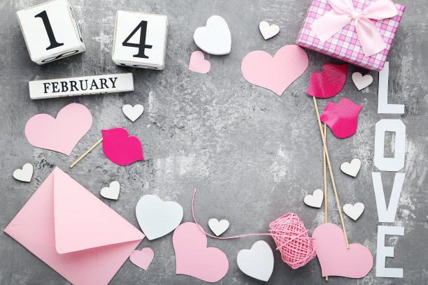 灰色木桌上放着粉色的心形信封、礼品盒和立方体日历图片下载