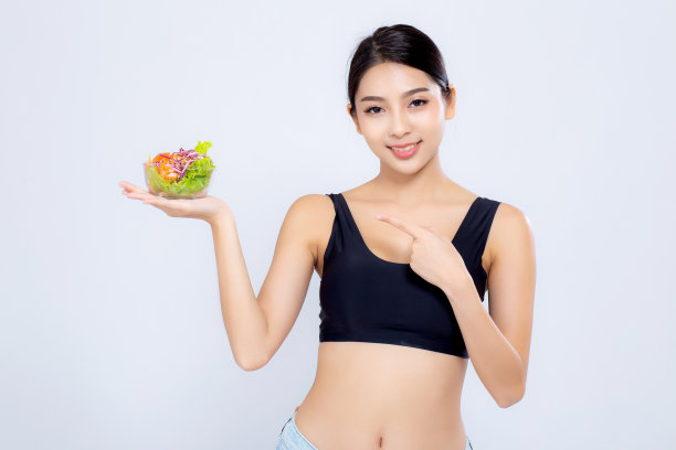 美丽的肖像年轻的亚洲女人微笑着拿和指着沙拉蔬菜食物孤立在白色的背景，女孩饮食吃素食的健康，保健或健康的概念。图片下载