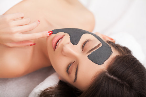 水疗中心。一个脸上戴着黏土面具的迷人有趣的女人图片下载