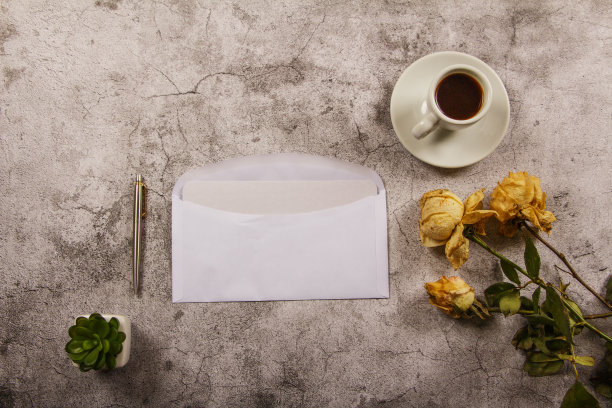 在灰色的混凝土背景上，用枯萎的白玫瑰花、干净的信封、记事本和一杯咖啡来模拟模板。从以上观点。平的。模板布局设计器。图片下载