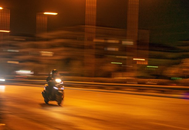夜间行驶在路上的滑板车。滑板车用平移技术拍摄。图片下载