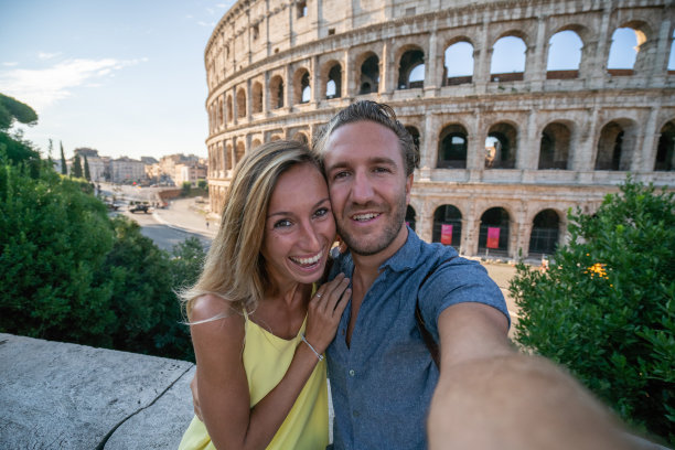 一对年轻夫妇在罗马享受意大利旅行，在著名的罗马斗牛场前拍照图片下载